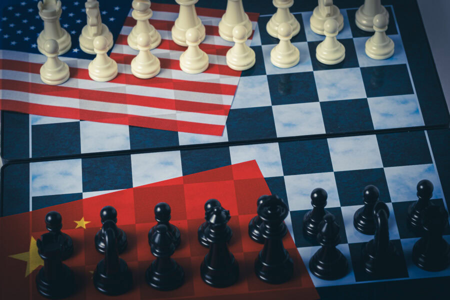 Chess board and chess pieces on flag united states america and china.