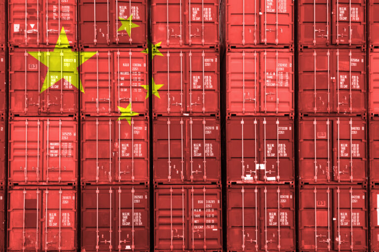 China flag over stack of containers at a port